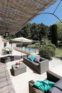 a patio with a couch and tables and an umbrella at Villavos- La Vassal in Cassis
