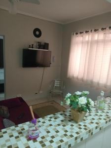 a living room with a table with flowers on it at Edifício Cannes AP 16A in Praia Grande