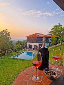 two glasses of wine on a table next to a pool at Cimo da Vinha - Nature Spot in Castelo de Paiva