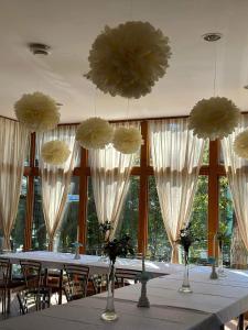 a dining room with a long table with white tables and flowers at U Karola in Karpicko +17 photos