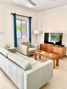 a living room with a couch and a flat screen tv at Maison Marie Jeanne - Unit 1 in Baie Sainte Anne