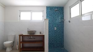 a bathroom with a toilet and a shower with blue tiles at Maison Marie Jeanne - Unit 1 in Baie Sainte Anne