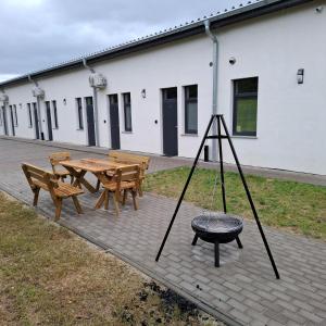 ein Holztisch und Stühle und ein Tisch und ein Grill in der Unterkunft Słoneczne pokoje nad jeziorem Nyskim in Skorochow
