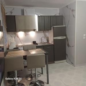 a kitchen with a refrigerator and a table and chairs at Cleopatra Apartment in Himare