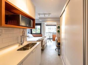 a kitchen with a sink and a living room at BHomy Medeiros in Sao Paulo