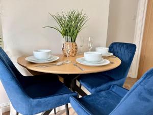 a dining room table with blue chairs and a table with plates and glasses at The Cosy Cwtch 2BR Apartment in City Centre in Cardiff +11 photos