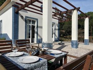 Una mesa con platos y copas de vino en un patio. en Casa da Lua, en Erra