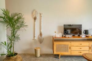 a living room with a wooden cabinet and a plant at Penida Green Palm Cottage by Bali Cabin in Toyapakeh