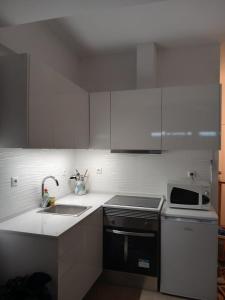 a white kitchen with a sink and a microwave at Monte Gordo Beach Sky Flat in Monte Gordo