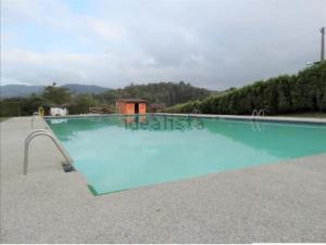 a large swimming pool with blue water in a yard at Piso Encanto Palmeiro in Jove