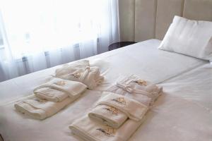 兹拉蒂博尔Modena Resort Spa & Wellness Zlatibor的白色床上的一组毛巾