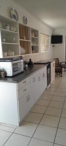 a kitchen with white cabinets and a microwave on a counter at Our Little House in Franskraalstrand +7 photos