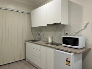 a kitchen with white cabinets and a microwave on a counter at Peaceful Studio Hidden in Kingsgrove in Sydney