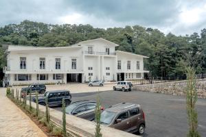 a large white building with cars parked in a parking lot at Rooms at Ratson in Shillong