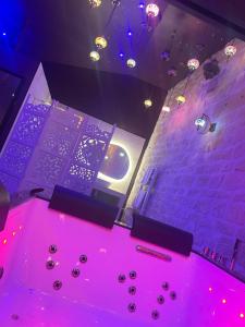 a room with a table with pink lights and a wall at Appartement Jacuzzi Hammam 1001 Nuits Yaospa60 in Montataire
