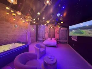 a purple room with a tub and a tv at Appartement Jacuzzi Hammam 1001 Nuits Yaospa60 in Montataire