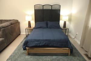 a bedroom with a bed with a blue bedspread and a couch at 1 Bedroom studio apartment in Daniels