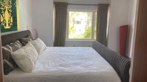 a bedroom with a white bed with a window at 2 Zimmerwohnung, offene Küche und grosser Wohnbereich mit Poolblick in Cabarete wenige Schritte vom Meer in Cabarete