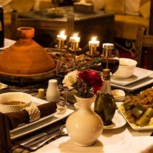 a table with plates of food and candles on it at Desert luxury tents in Merzouga