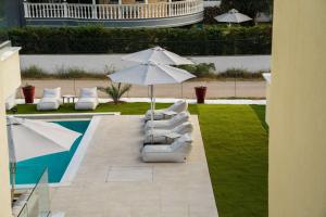 a patio with an umbrella and chairs and a pool at Ethéreal Thassos in Limenas