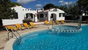 a pool with chairs and a house in the background at Binibasket in Ciutadella
