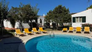 a swimming pool with yellow chairs and a group oficans at Binibasket in Ciutadella