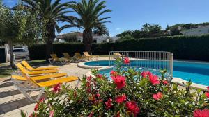 a patio with chairs and a swimming pool with flowers at Binibasket in Ciutadella