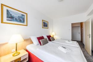 a bedroom with a large white bed with a lamp on it at Hotel Oáza Praha in Prague