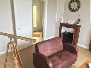 a living room with a chair and a clock on the wall at La Maison de la Rose in Étretat +61 photos