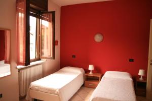 una camera con due letti e una parete rossa di Locanda Del Centro a Cambiano