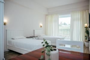 Un dormitorio blanco con dos camas y una ventana. en Rooms at Ratson, en Shillong