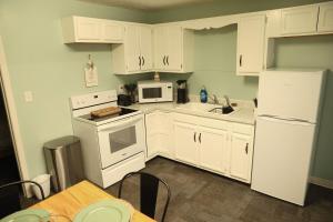 a white kitchen with white appliances and a table at 2 Bedroom Unit in Daniels