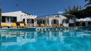 a swimming pool with blue water in front of a house at Binibasket in Ciutadella +30 photos