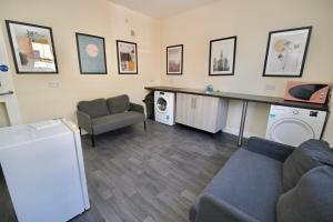 a living room with a couch a table and a washing machine at Belgrade Lodge Studio 4 - Parking, City Centre, Walk to West Orchard Shopping Centre in Coventry