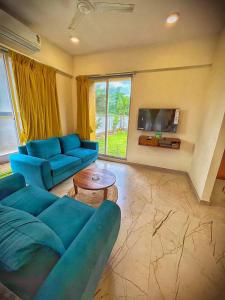 a living room with a blue couch and a tv at Viroha, Dahanu - Luxury 3BHK Farm Arvind Villa - 121 