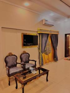 a living room with two chairs and a coffee table at Galaxy Rezidor in Karachi