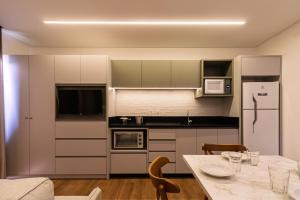 a kitchen with a table and a white refrigerator at Flats Four Seasons by RD Stays in Bombinhas
