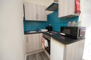 a small kitchen with a microwave and a sink at Belgrade Lodge Studio 7 - City Centre, WiFi, Free Netflix, Parking in Coventry