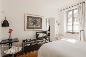 a white bedroom with a bed and a tv at La Cour de Beaune in Beaune