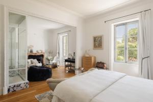 a white bedroom with a bed and a living room at La Cour de Beaune in Beaune
