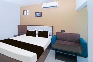 un dormitorio con una cama y una silla en Super Hotel O MG International, en Jamshedpur 21 fotos más