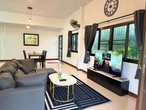 a living room with a couch and a tv at เฮือนแม่บัวจันทร์ โฮมสเตย์ in Chiang Kham