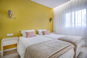 two beds in a room with a yellow wall at Agua Hotels Vila Branca in Lagos