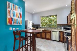 ココにあるModern Island-Themed Condo with Floor-to-Ceiling Windows & Garden and Pool Views Within Walking Distance of the Beachの木製のテーブルと青い壁のあるキッチン