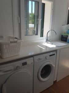 a white laundry room with a sink and a washing machine at Agua en las Rocas in Sa Caleta