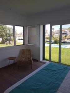 a room with a bed and a chair and windows at Agua en las Rocas in Sa Caleta
