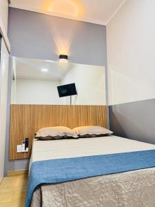 a bedroom with a bed with a wooden headboard at Residencial Aurelio Souza Studios in Pouso Alegre
