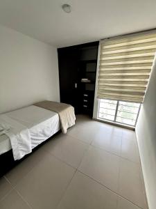 Un dormitorio con una cama y una ventana grande. en Descanso y Comodidad en Edificio Seguro con Balcón, en Floridablanca