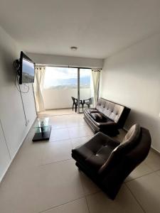 Una sala de estar con un sofá de cuero y un televisor. en Descanso y Comodidad en Edificio Seguro con Balcón, en Floridablanca