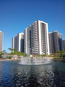 a fountain in a pond in front of tall buildings at Apart Hotel Barra Bela Barra da Tijuca in Rio de Janeiro